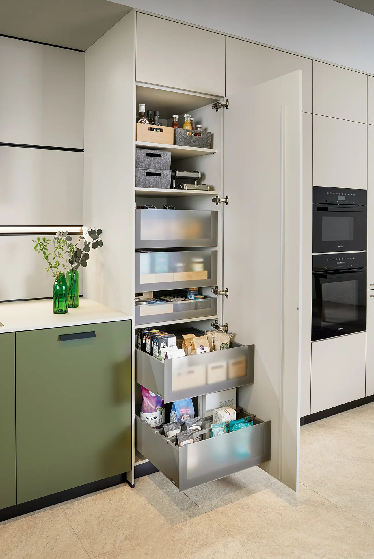 Larder storage with drawers beside tall ovens
