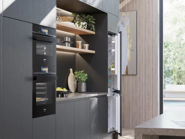 Built-in black ovens and fridge freezer in a dark kitchen
