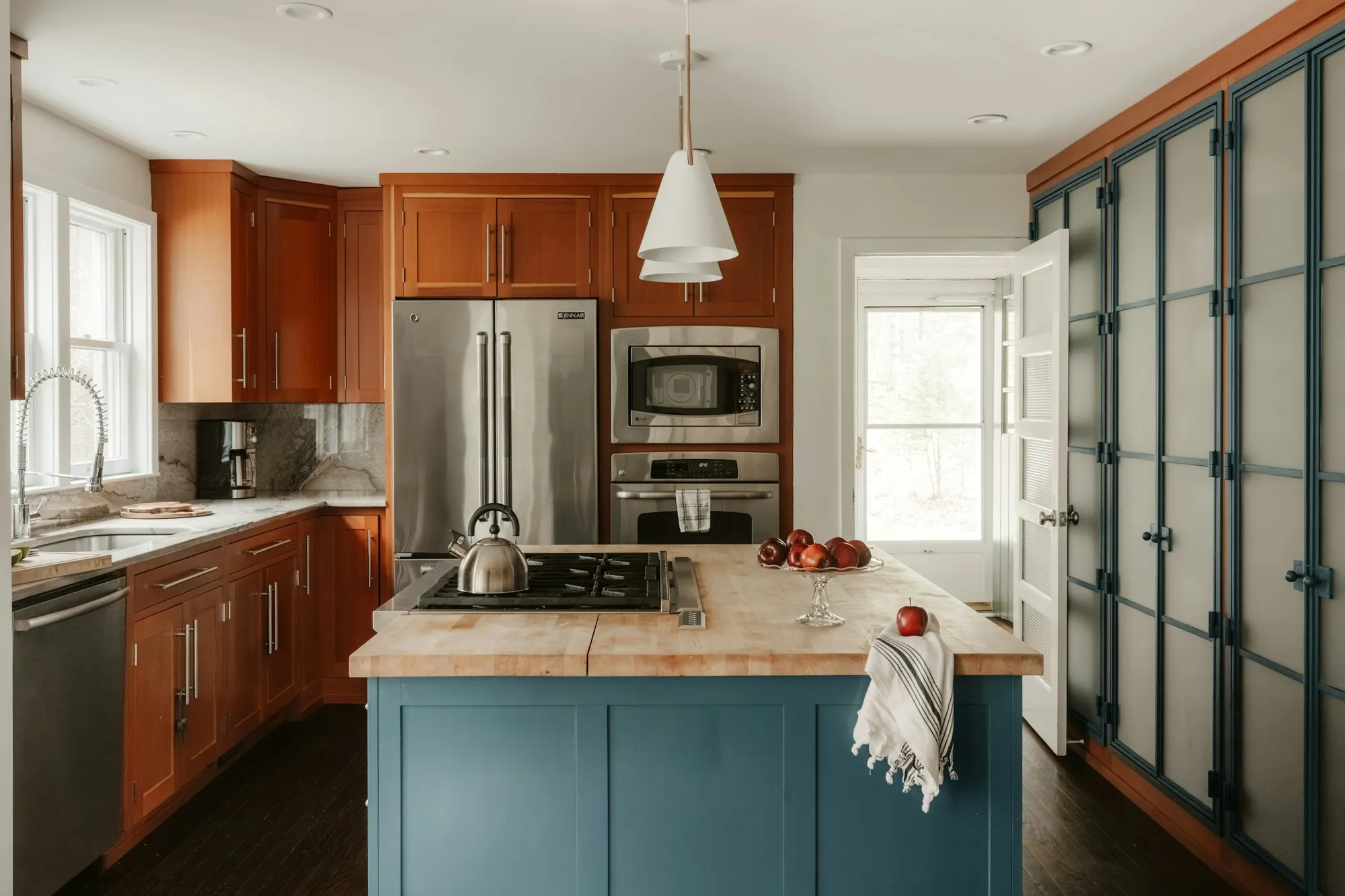 Kitchen with a blue island, timber worktop and warm wood cabinets
