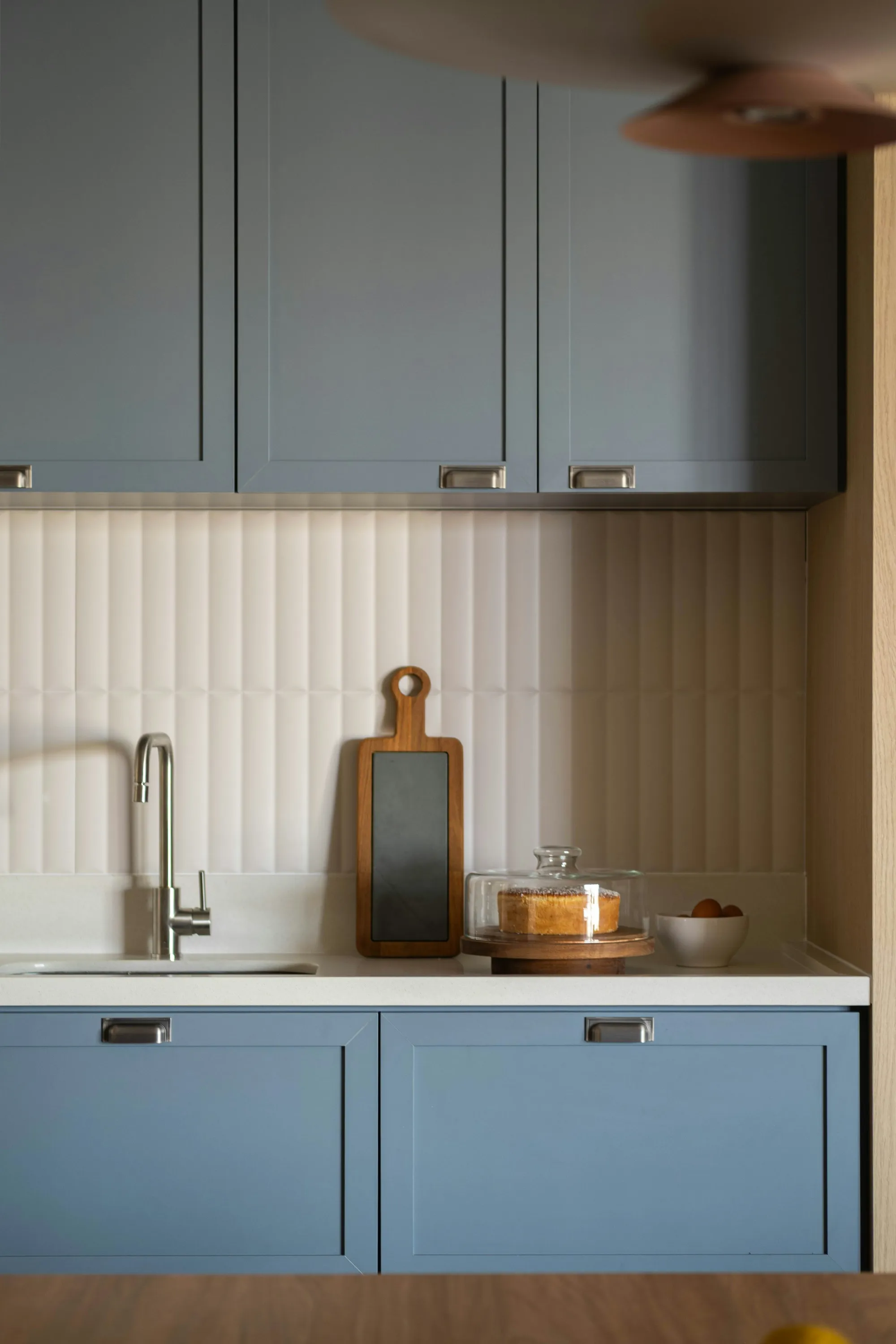 Blue-grey shaker cabinets with a ribbed white splashback