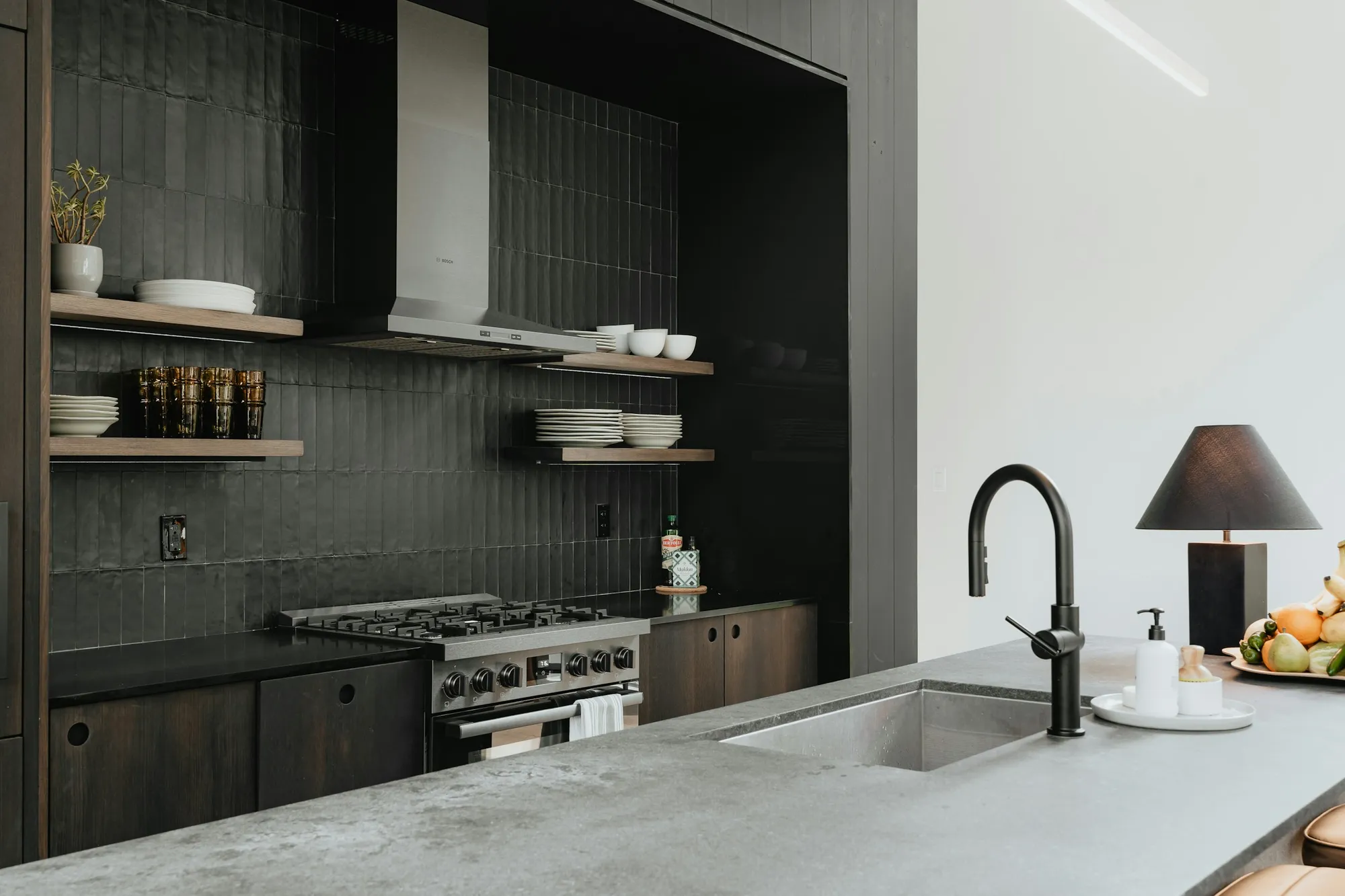 Charcoal kitchen with dark tiles, open shelves, a black tap and a concrete-look worktop