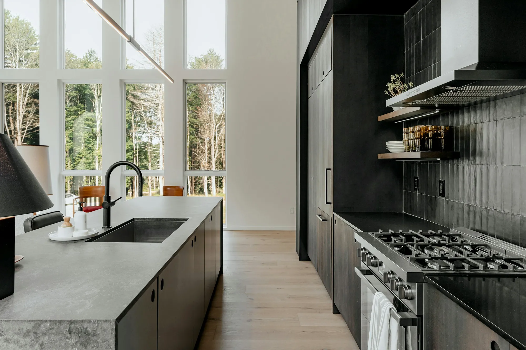 Dark kitchen island with a grey worktop beside tall windows