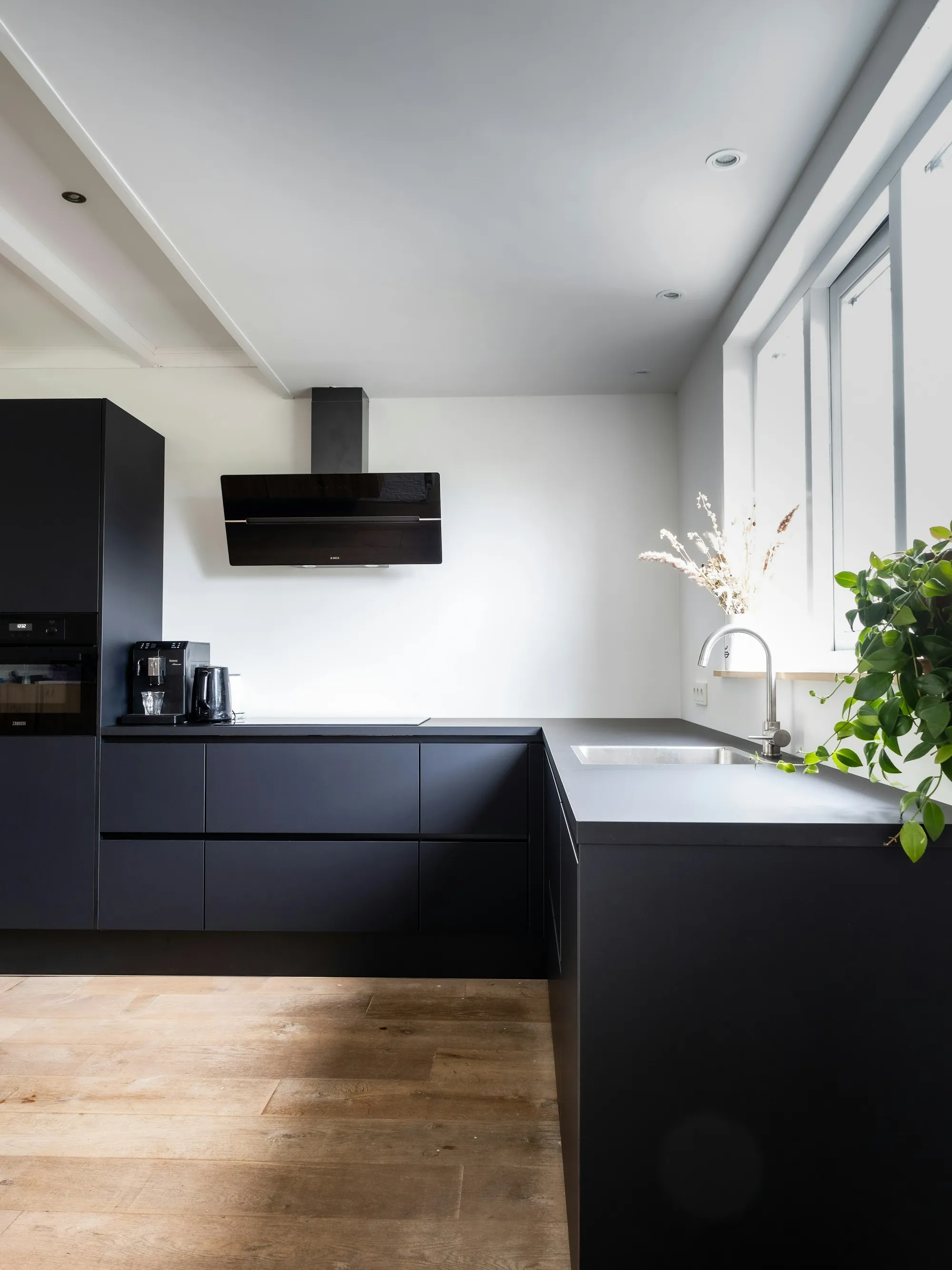 Matt black handleless kitchen with a bright window