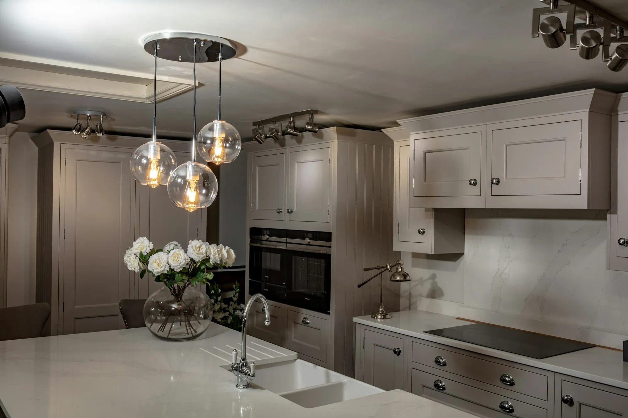 Taupe shaker kitchen with a marble island and glass pendant lights