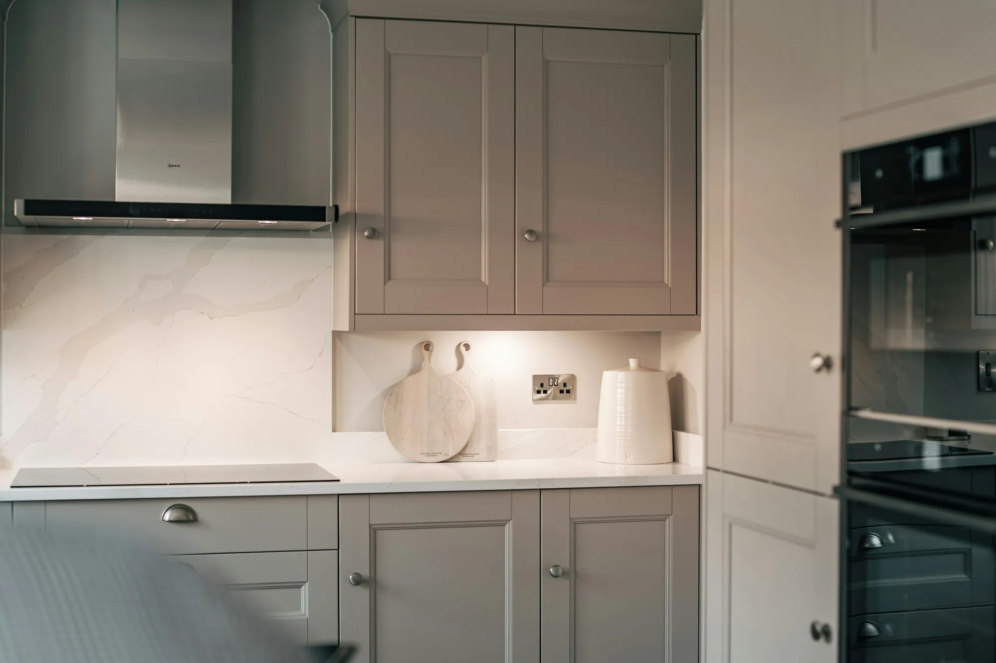 Taupe shaker wall cabinets with a marble splashback