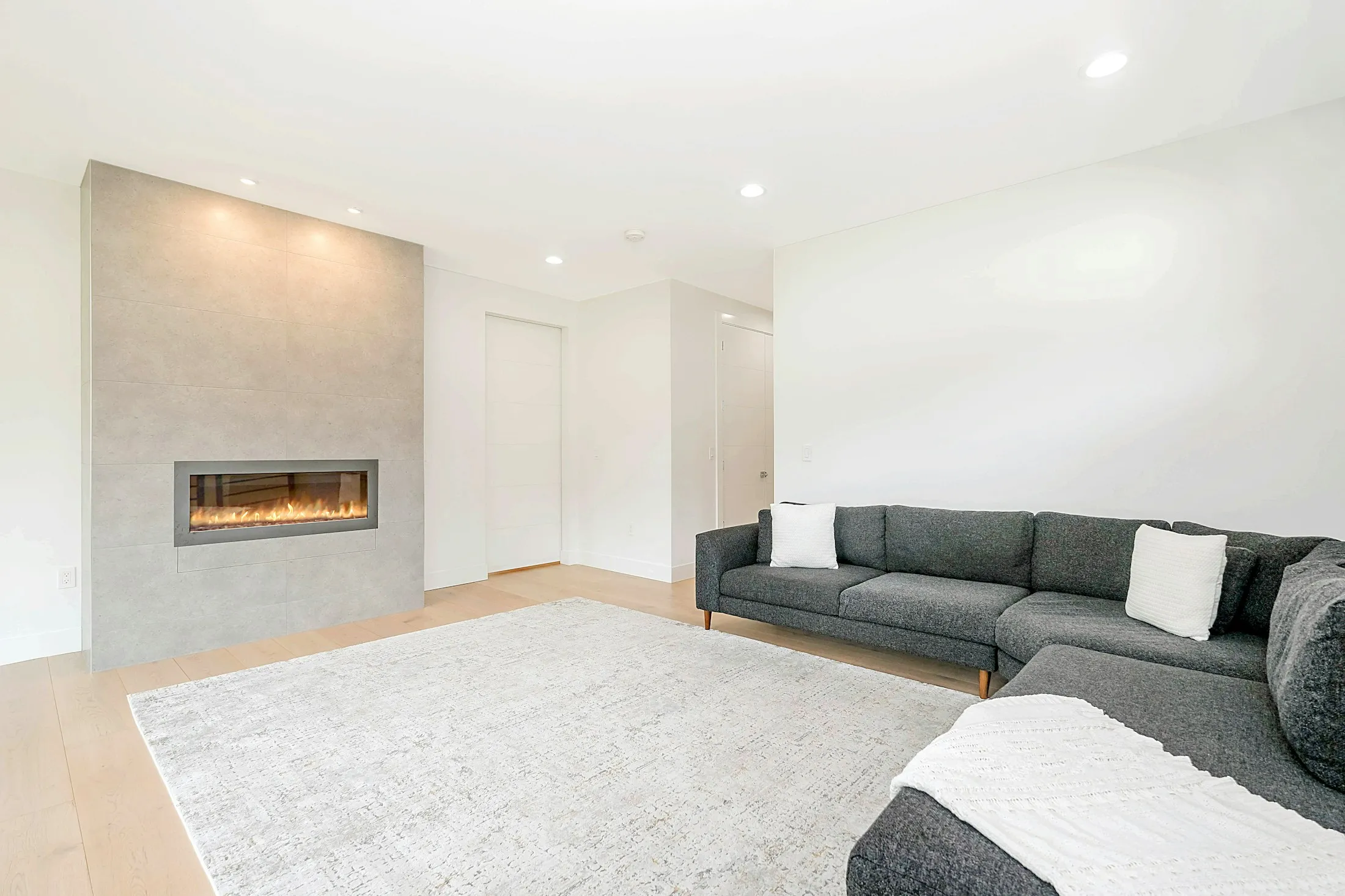 White living room with a linear fireplace and a grey sofa