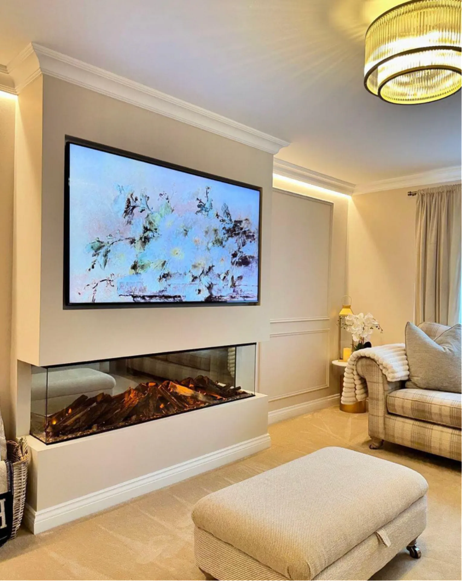 British Fires three-sided electric fire set into a media wall below a wall-mounted television in a cream living room