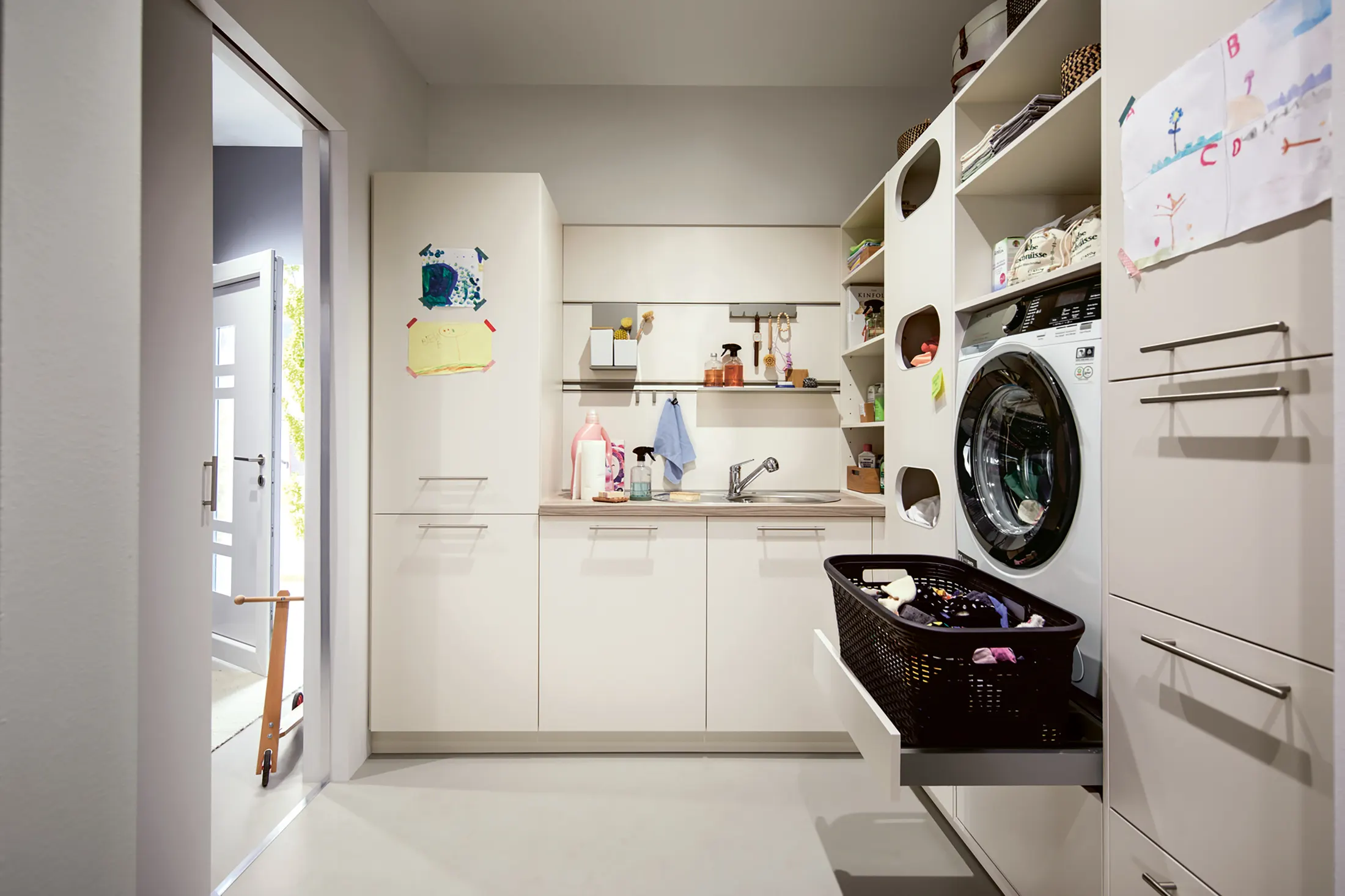 White fitted utility room cabinets with a washing machine and open shelving
