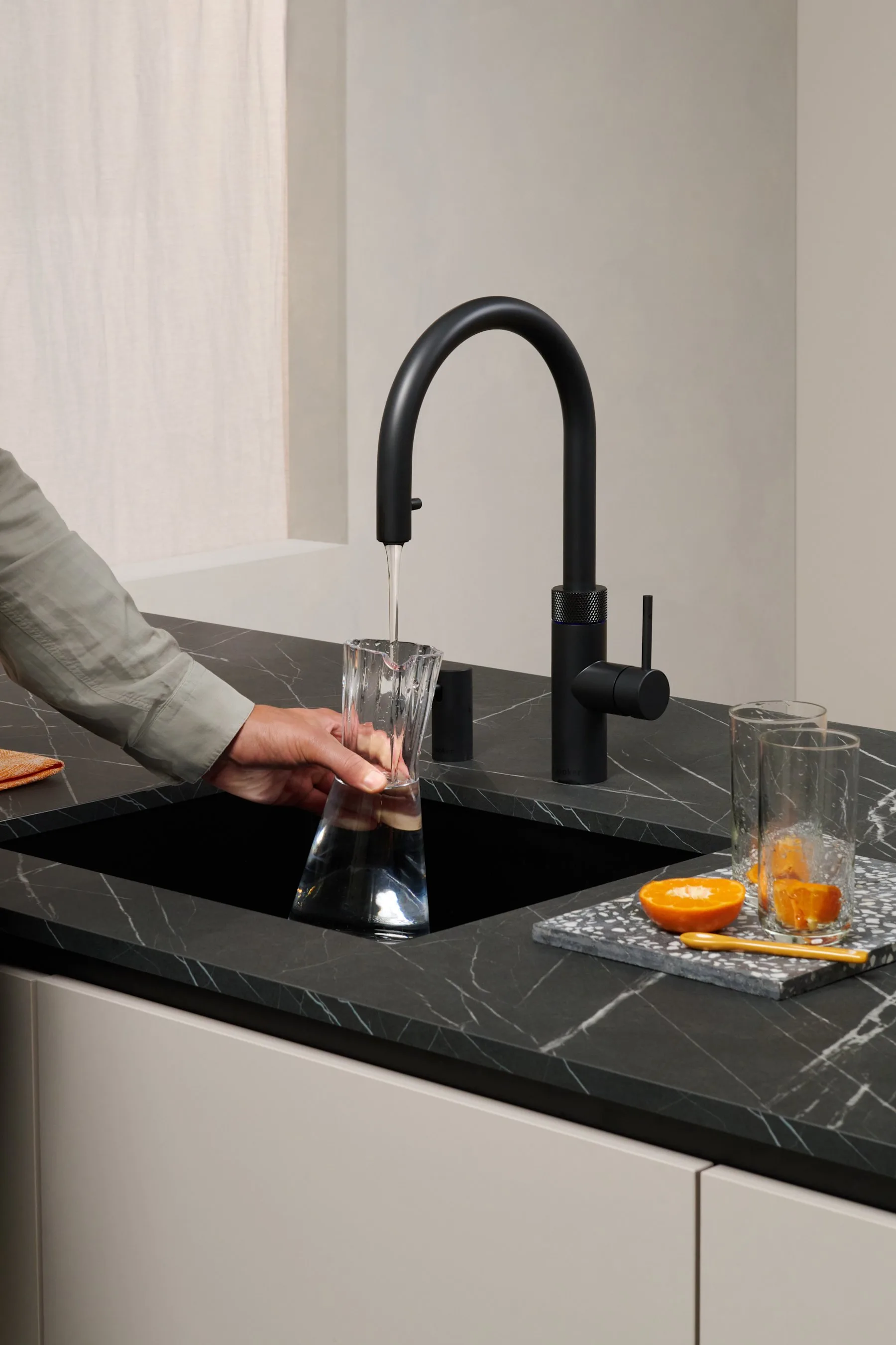 Filling a glass with chilled filtered water from a matt black Quooker Flex tap