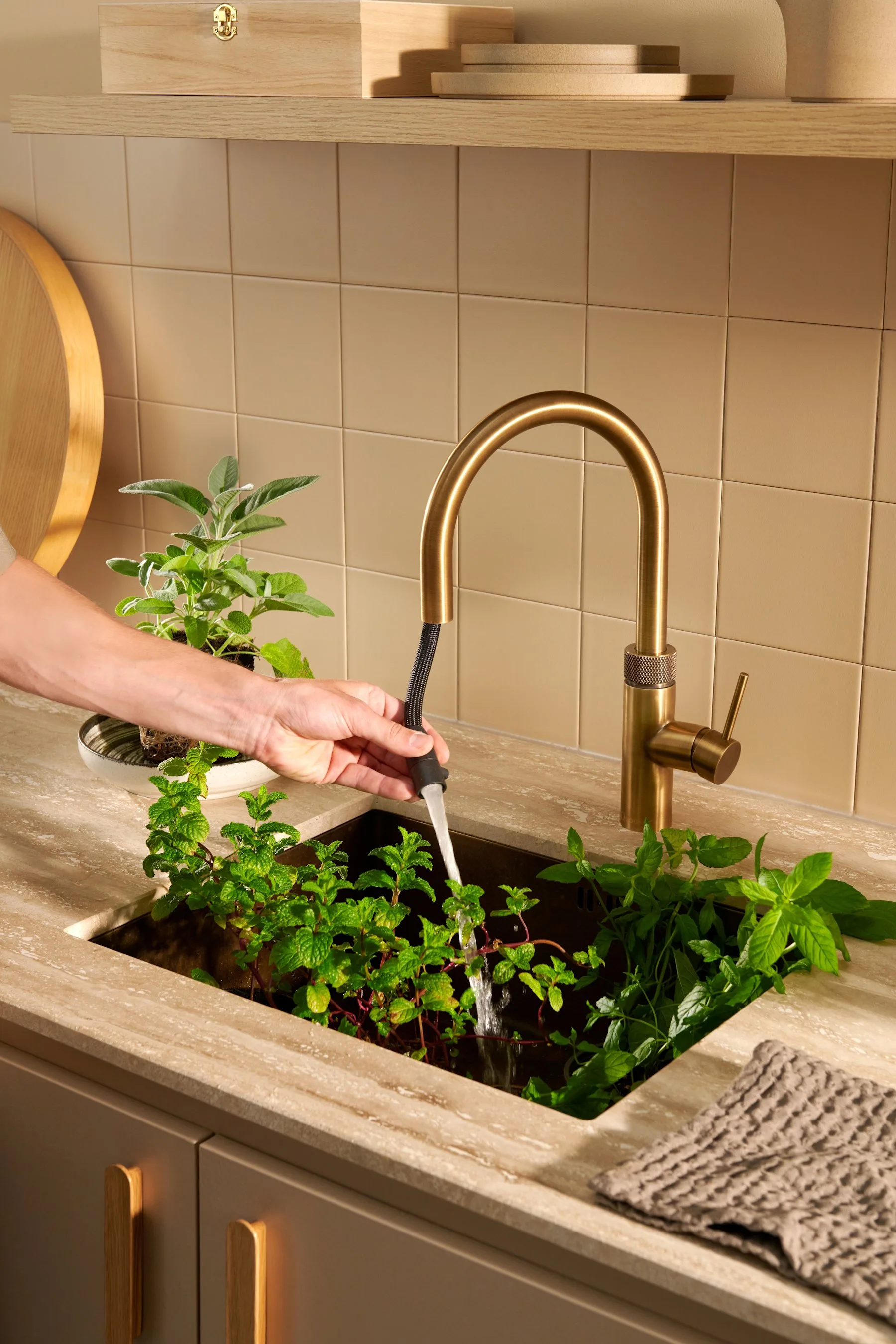 Rinsing fresh herbs in an undermount sink with the Quooker Flex pull-out hose in patinated brass