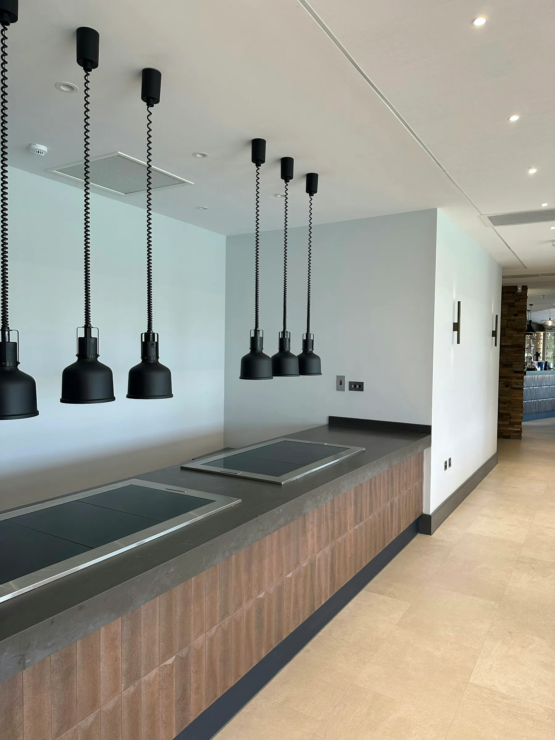Integrated induction hobs beneath black pendant lights