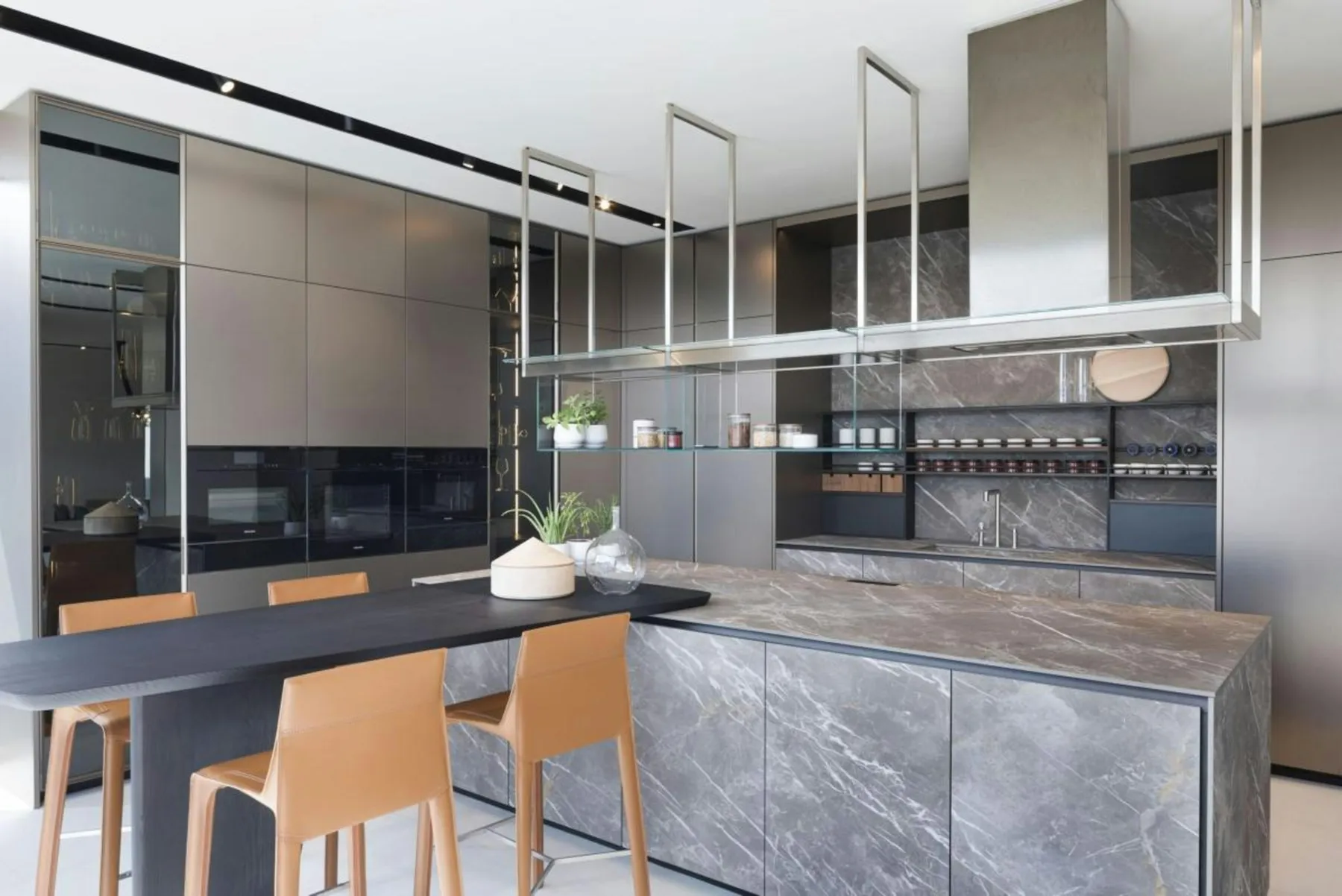 Kitchen with a grey stone island, oak bar stools and a suspended extractor