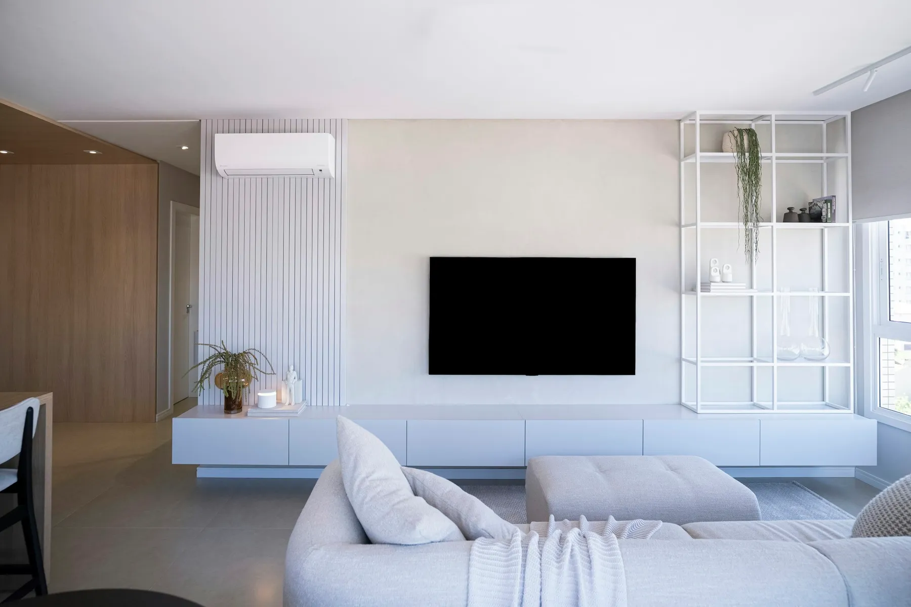 White media wall with a floating unit and a television in a bright living room